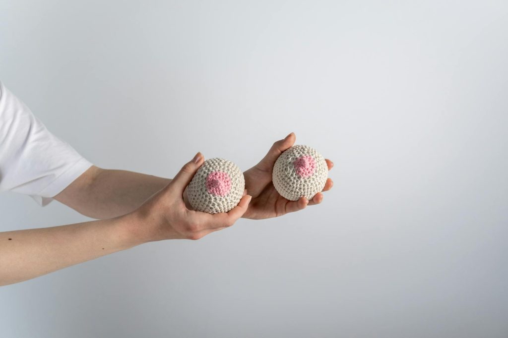 a person holding beige and pink knitted breast